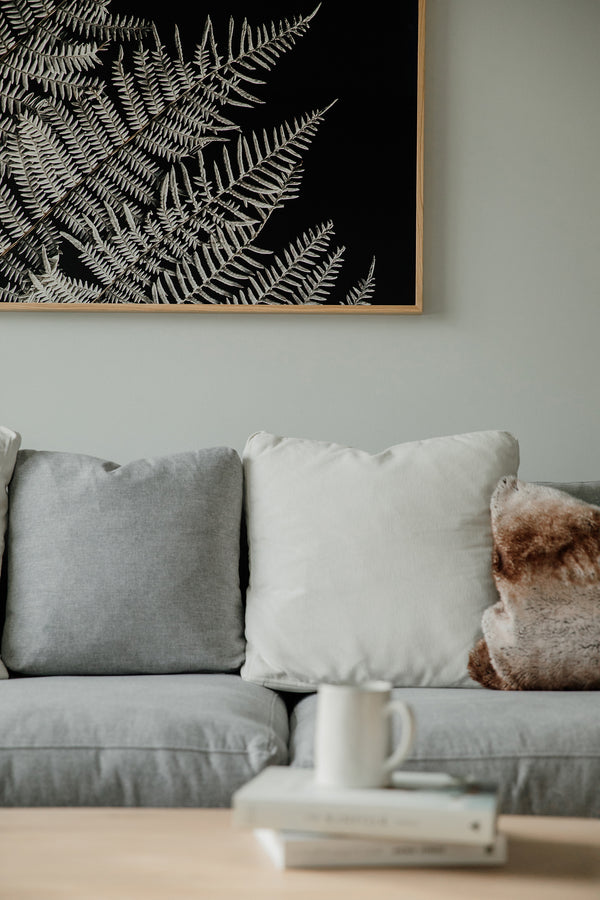 Large Scale Premium Floral Wall Art in a cozy, comfortable and warm interior design space. The premium quality of the paper elevates the floral designs that are photographed and hung in the living room. Interior Design magazine, mug blurry in foreground
